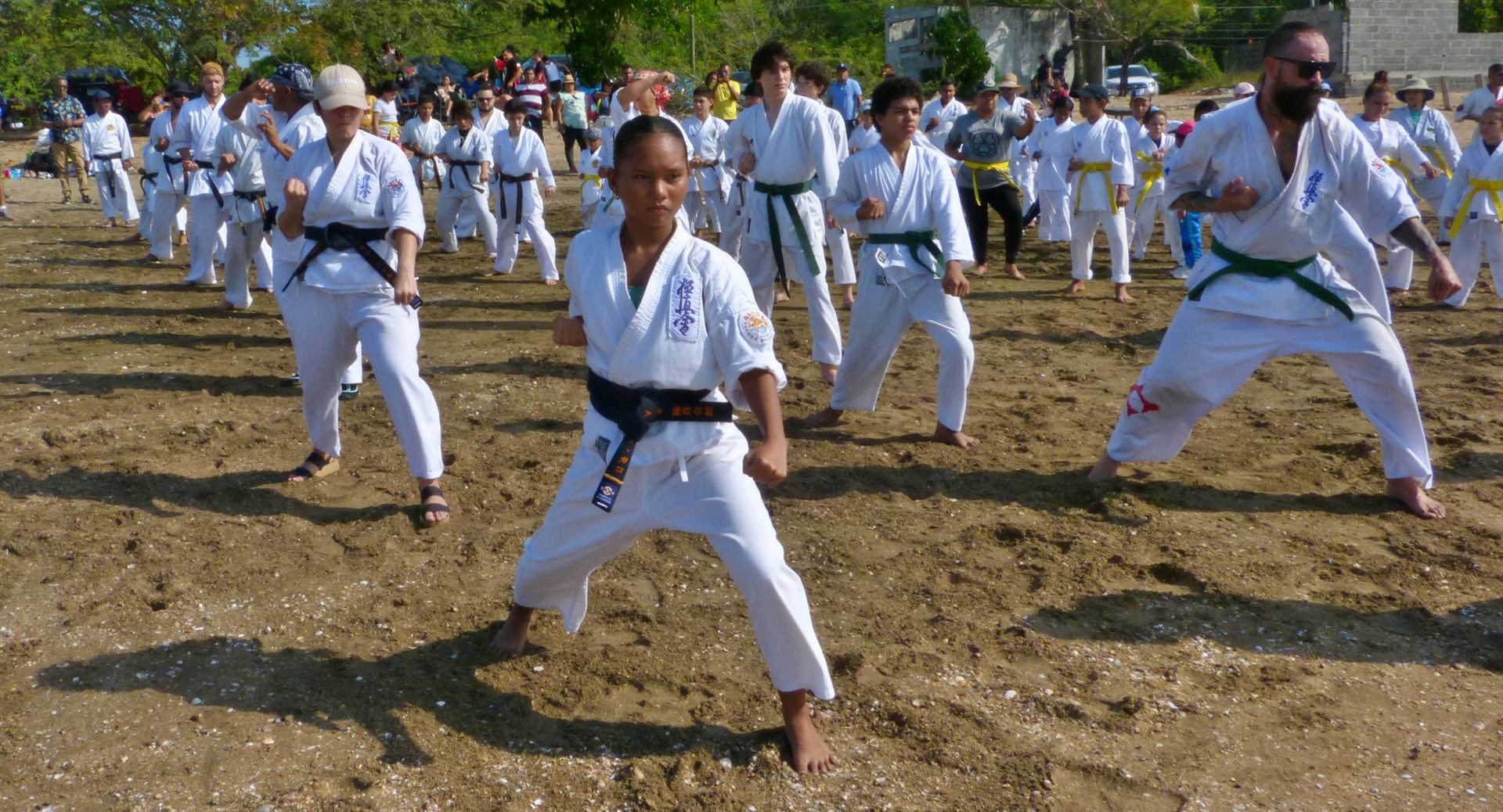 Decenas de karatecas del dojo entrenando en la playa durante el Kagami Biraki
