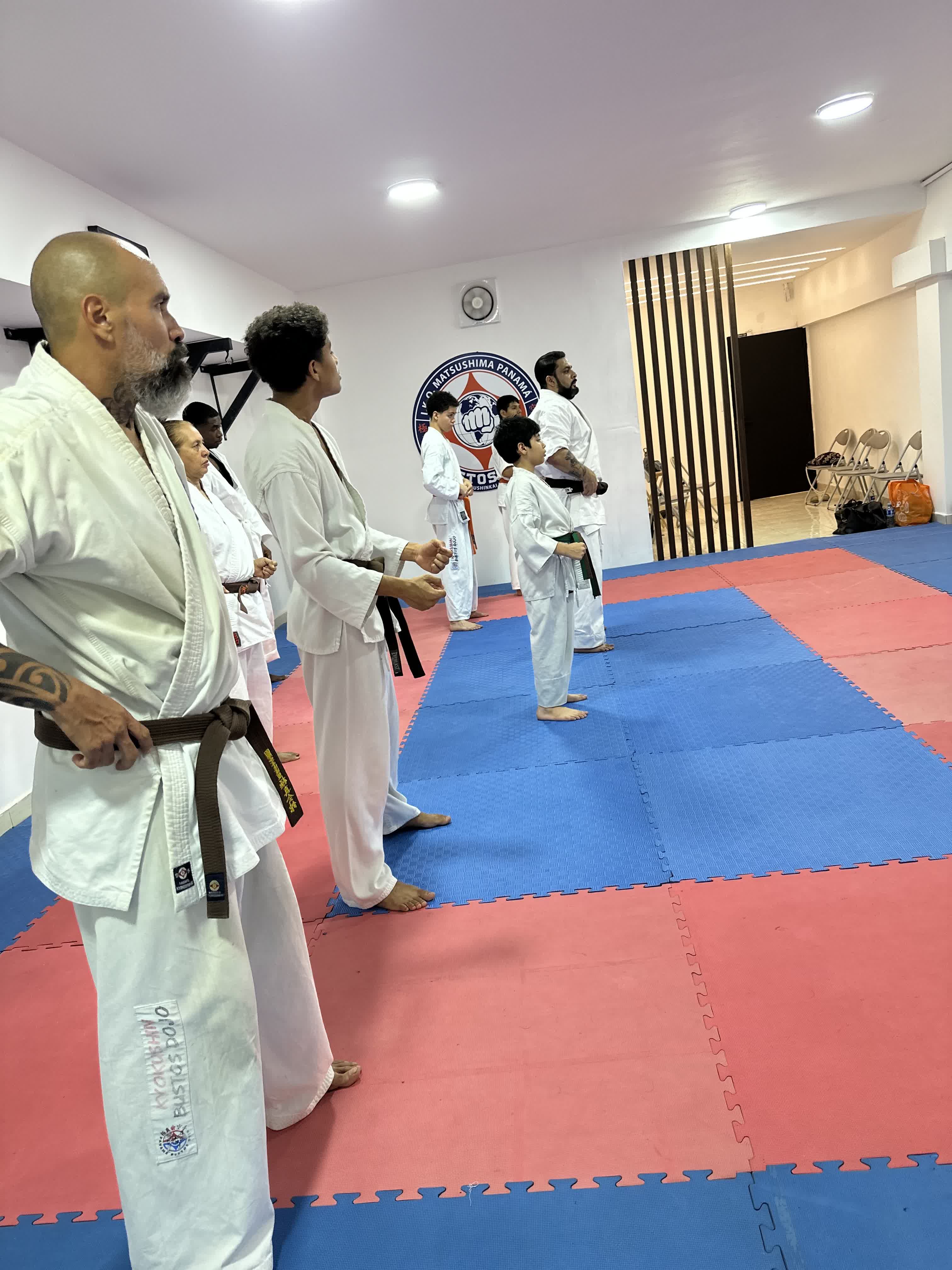 Alumnos del Kaizen Dojo alineados frente al emblema de I.K.O. Matsushima Panamá en nuestra sede